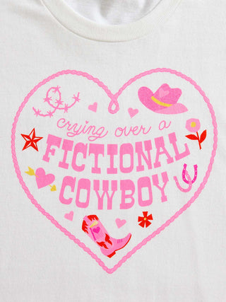 A close-up of a white crewneck t-shirt featuring a pink heart-shaped graphic with the text 'crying over a FICTIONAL COWBOY' and western-themed illustrations.