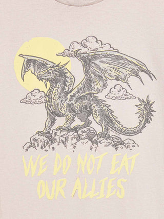 A close-up of a light beige t-shirt featuring a graphic print of a black line-art dragon under a yellow sun and clouds, with the text 'WE DO NOT EAT OUR ALLIES' printed below in yellow.