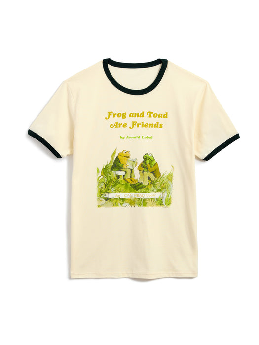 A cream-colored ringer t-shirt with forest green trim on the collar and sleeve cuffs, featuring a colorful graphic of a frog and toad sitting on grass with the text 'Frog and Toad Are Friends' by Arnold Lobel.