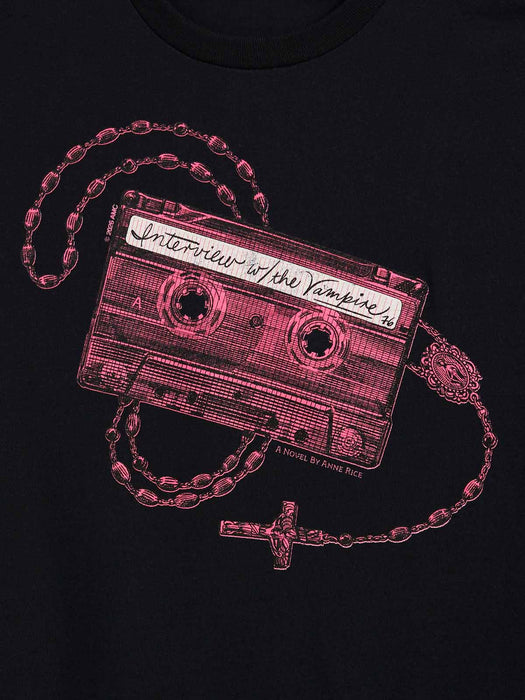 A close-up of a black t-shirt featuring a graphic print of a cassette tape with a rosary with a cross, with the tape label reading 'Interview with the Vampire'.