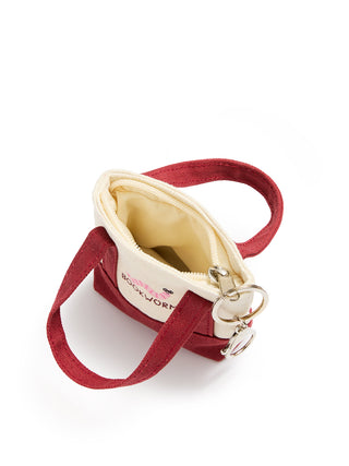 A small canvas zippered pouch with a burgundy fabric exterior, cream interior lining, and a matching burgundy strap attached with silver metal rings. The front features a cream canvas panel with the text 'BOOKWORM' in red.