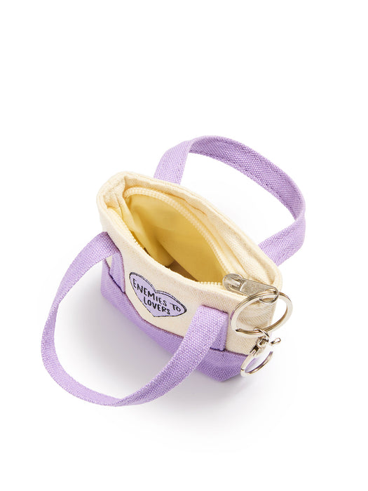 A small lavender canvas shoulder bag with a cream-colored interior lining, a circular 'Enemies to Lover' patch, and silver metal key rings, shown on a white background.