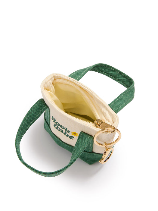 A small canvas pouch with green fabric handles and trim, a cream-colored interior, and a gold-tone key ring attachment. The front of the pouch features the text 'Book Babe' with a small yellow flower logo.