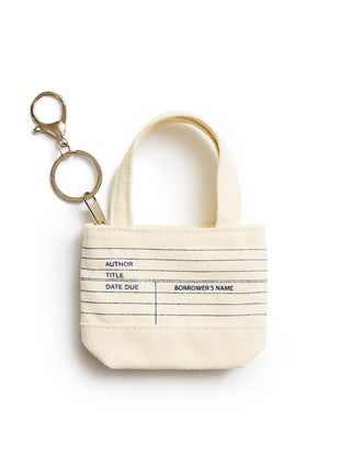 A small canvas tote keychain in cream with navy blue lined borrowing form text, featuring a gold-tone metal clasp and key rings, on a white background.