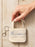 A hand holding a small canvas library bag keychain with a silver key ring, printed with 'AUTHOR', 'TITLE', 'DATE DUE', and 'BORROWER'S NAME' on a light wood plank background.