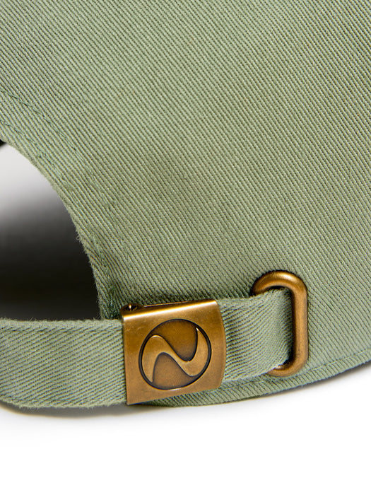 Close-up of the back strap of a green cap with a brass buckle featuring a stylized 'Z' logo.