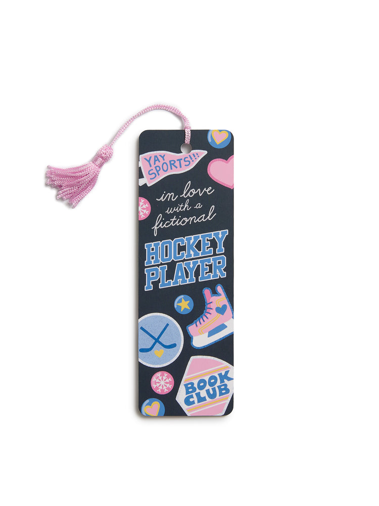 A dark navy book club bookmark with a pink tassel, decorated with colorful hockey-themed stickers and text including 'YAY SPORTS!', 'in love with a fictional HOCKEY PLAYER', and 'BOOK CLUB'.