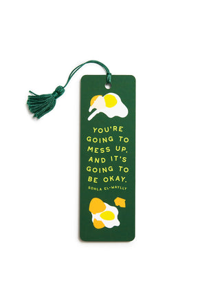 A dark green bookmark with a matching green tassel, featuring a fried egg illustration and the quote 'YOU'RE GOING TO MESS UP. AND IT'S GOING TO BE OKAY.