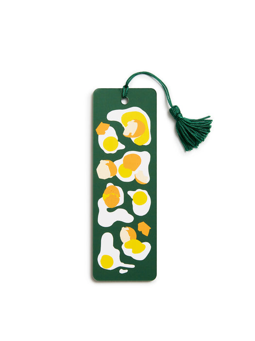 A dark green rectangular bookmark with a tassel, decorated with a minimalist abstract pattern of fried eggs in yellow, orange, and white, on a solid white background.
