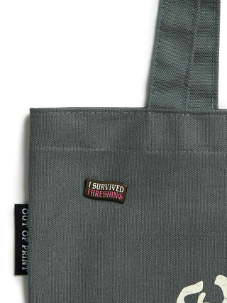 Gray tote bag with a label reading 'I Survived Thieving' on a white background