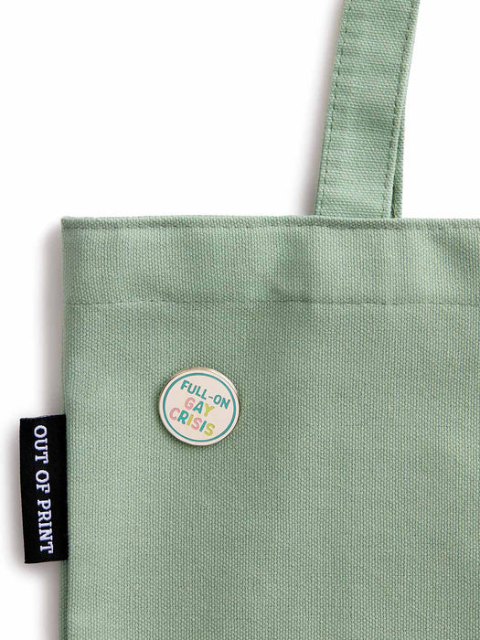 Green tote bag with a circular patch and 'Out of Print' tag on a white background