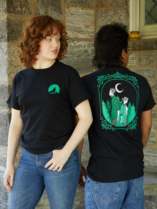 Two people wearing black t-shirts with green designs, one on the front and one on the back, against a stone wall.