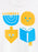 A close-up of a white garment featuring a colorful graphic print of four festive symbols: a blue menorah, a yellow latke, a yellow dreidel, and a blue open book with a yellow bookmark.