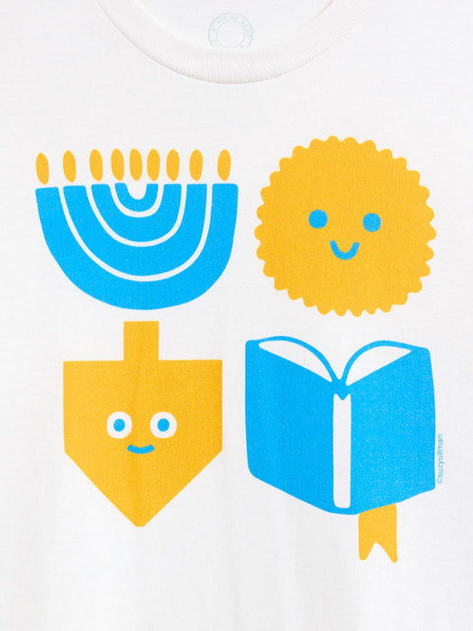 A close-up of a white garment featuring a colorful graphic print of four festive symbols: a blue menorah, a yellow latke, a yellow dreidel, and a blue open book with a yellow bookmark.