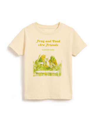 A cream-colored short-sleeve t-shirt featuring a graphic print of a green frog and a yellow-green toad sitting on a log, with the text 'Frog and Toad Are Friends' and 'by Arnold Llobel' printed above them.