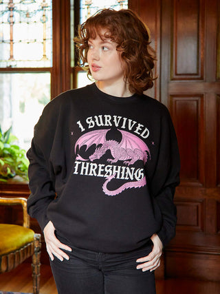 Person wearing a black sweatshirt with a dragon graphic and text in a room with wooden paneling.
