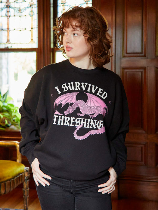 Person wearing a black sweatshirt with a dragon graphic and text in a room with wooden paneling.