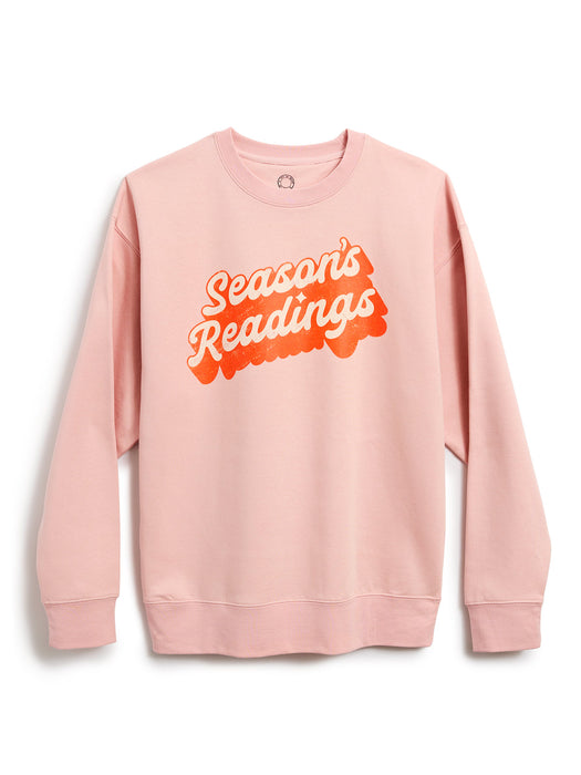 A light pink crewneck sweatshirt featuring a retro-style graphic on the chest that reads 'Season's Readings' in bubble lettering, displayed against a clean white background.