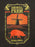 A graphic print featuring the words 'ANIMAL FARM' and 'GEORGE ORWELL' with a stylized illustration of a windmill, sunburst, plowed field, and a pig, printed in yellow and orange-red on a dark background.