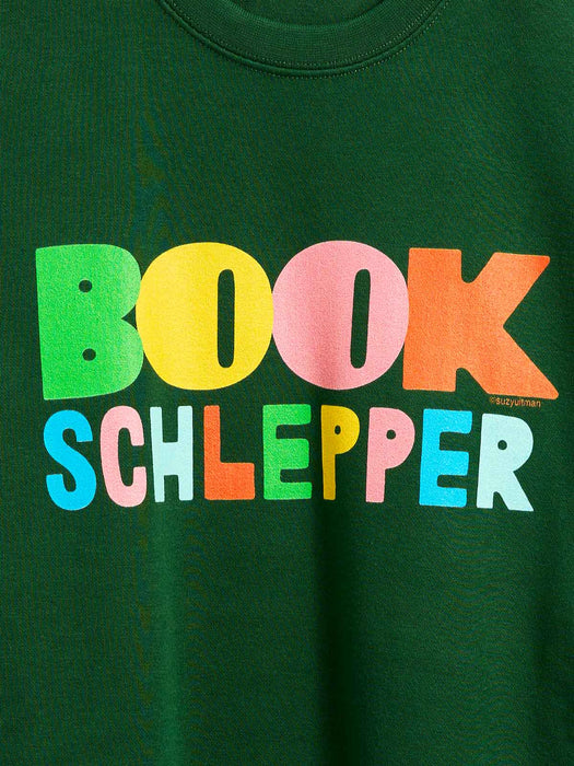 A close-up of a dark green sweatshirt featuring the text 'BOOK SCHLEPPER' printed in large, colorful letters across the chest.