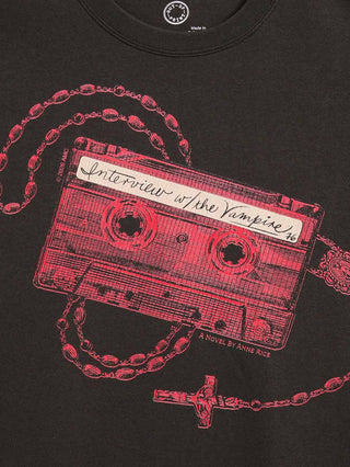 Close-up of a black graphic t-shirt featuring a red cassette tape illustration overlaid with a rosary chain and cross, with the text 'Interview with the Vampire' and 'A Novel by Anne Rice' printed on the design.