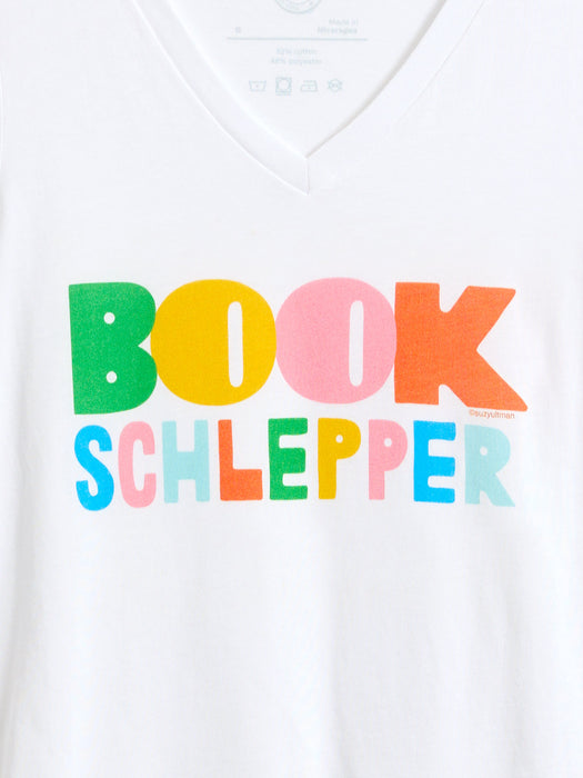 White V-neck t-shirt featuring a colorful graphic print that reads 'BOOK SCHLEPPER' in bold, multicolored letters.