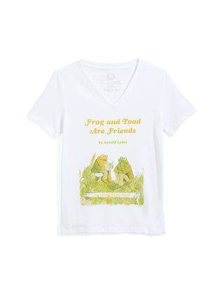 A white short-sleeve V-neck t-shirt featuring a graphic print of the classic 'Frog and Toad Are Friends' book cover, including the title in yellow text and an illustration of the characters on a green grassy field.