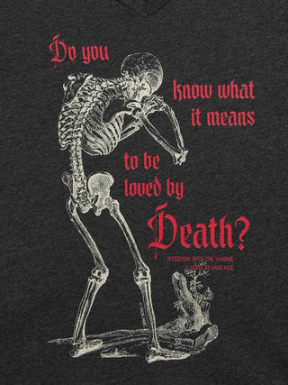 A dark heather gray v-neck t-shirt featuring a graphic print of a skeleton leaning forward with red gothic text that reads, 'Do you know what it means to be loved by Death?'.