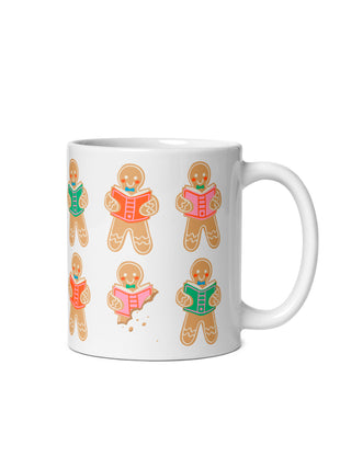 A white ceramic mug featuring a repeating pattern of gingerbread character illustrations reading books, shown against a plain white background.