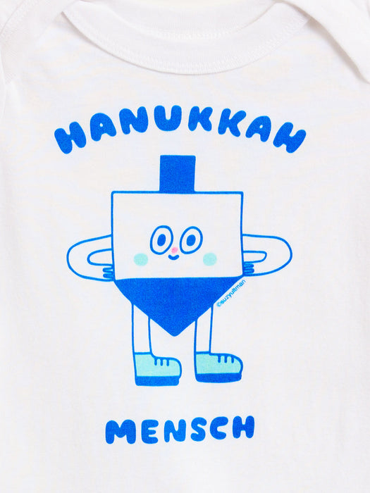 White baby bodysuit featuring a blue graphic of a smiling dreidel character with the text 'HANUKKAH' above and 'MENSCH' below.