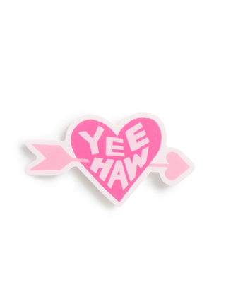 A pink heart-shaped pin with a white border, crossed by a pink arrow, featuring the text 'YEE HAW' in white lettering, set against a plain white background.