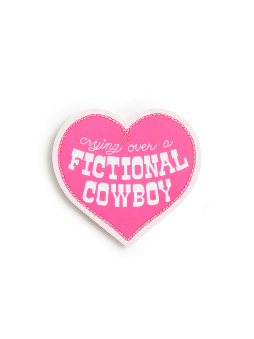 A heart-shaped pink patch with white text reading 'crying over a FICTIONAL COWBOY' on a plain white background.