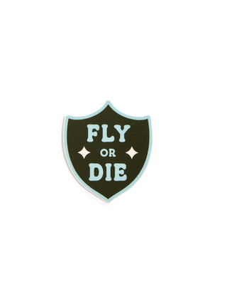 A shield-shaped sticker with a dark green center, light blue border, and the words 'FLY OR DIE' in light blue lettering, shown on a plain white background.