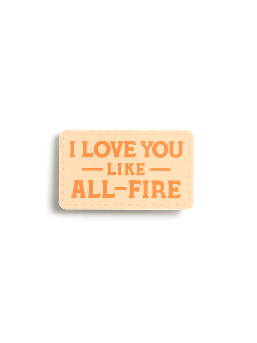 A rectangular patch sticker with rounded corners featuring the text 'I LOVE YOU LIKE ALL-FIRE' in orange lettering on a light peach-beige background, shown on a clean white background.