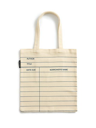 A cream-colored canvas tote bag with lined notebook-style writing guides and blue text fields for author, title, date due, and borrower's name, shown on a plain white background.