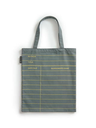 A slate gray canvas tote bag with gold horizontal lines and printed fields for author, title, date due, and borrower's name, shown against a plain white background.
