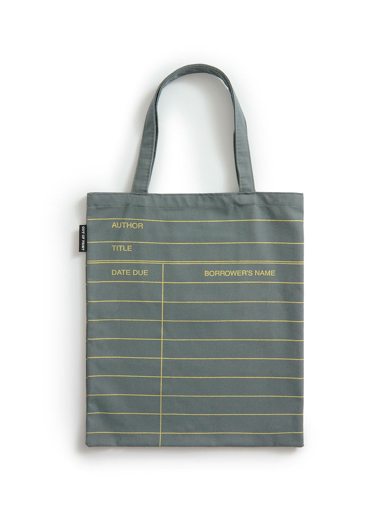 A slate gray canvas tote bag with gold horizontal lines and printed fields for author, title, date due, and borrower's name, shown against a plain white background.