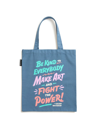 A blue canvas tote bag with long handles, featuring a colorful hand-lettered quote on the front that reads 'Be Kind to Everybody Make Art and Fight the Power! -Colson Whitehead'.