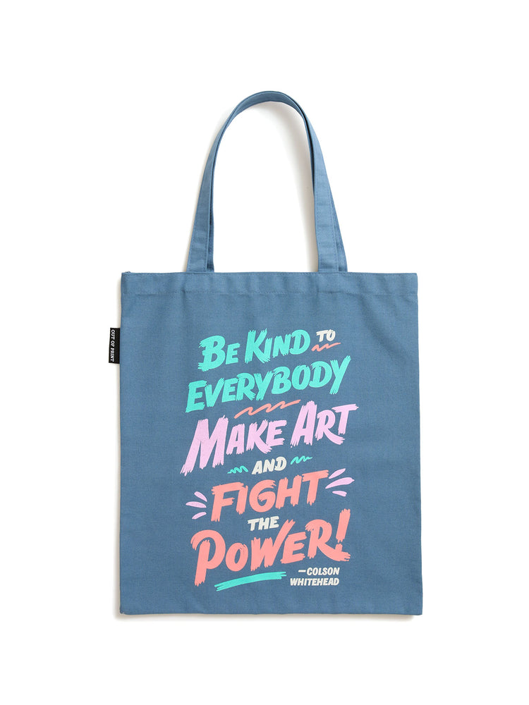A blue canvas tote bag with long handles, featuring a colorful hand-lettered quote on the front that reads 'Be Kind to Everybody Make Art and Fight the Power! -Colson Whitehead'.