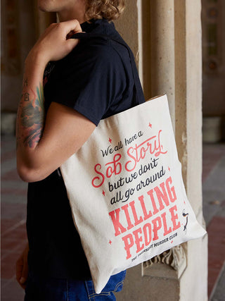 Person holding a tote bag with a red and black text design.
