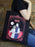 Person holding a tote bag with a 'Bride' design featuring a couple and moon.