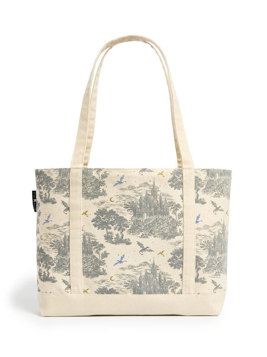 A canvas tote bag with a cream-colored base and handles, featuring a detailed gray toile-style print of castles, trees, and flying dragons, accented with small blue and gold motifs.