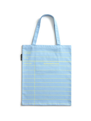 A light cloud blue canvas tote bag with yellow horizontal lines and yellow text, featuring two shoulder straps, photographed against a plain white background.