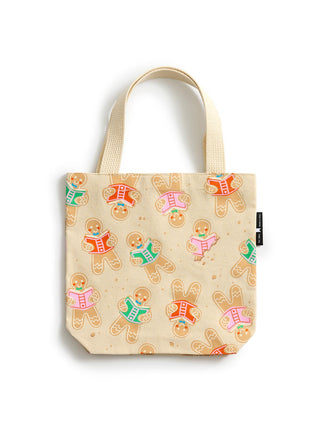 A cream canvas mini tote bag featuring an all-over print of gingerbread cookies reading books, with two top handles and a small black brand tag on the side.
