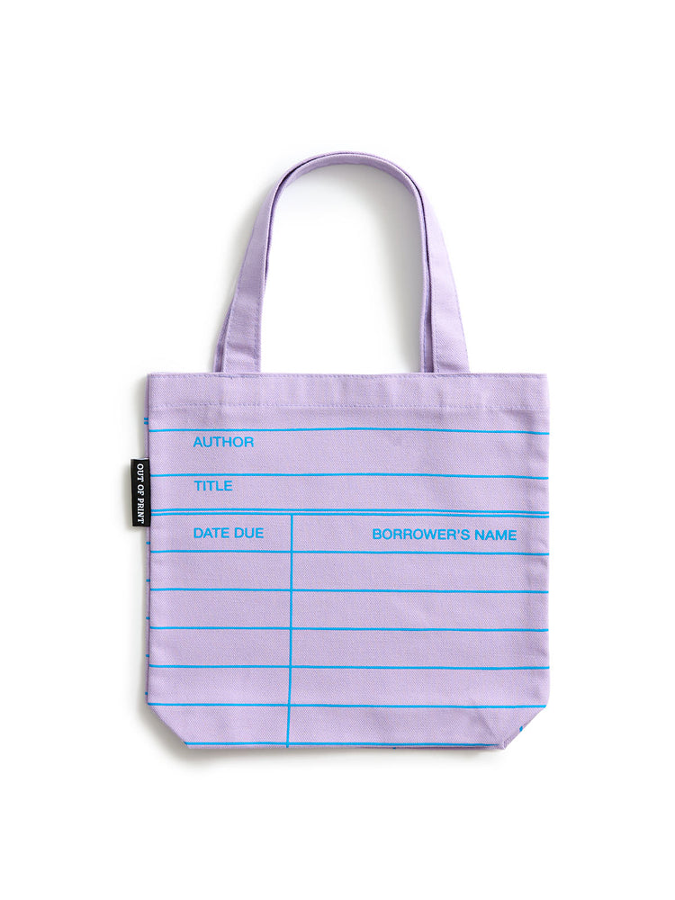 A lilac purple tote bag with blue printed lines and text fields for author, title, date due, and borrower's name, shown on a plain white background.