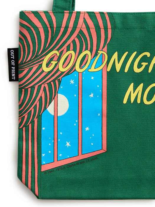 Closeup of a green canvas tote bag featuring a retro graphic of a curtain pulled open to reveal a starry night sky with a moon, alongside yellow text reading 'GOODNIGHT MO'. A black fabric tag on the left reads 'OUT OF PRINT'.